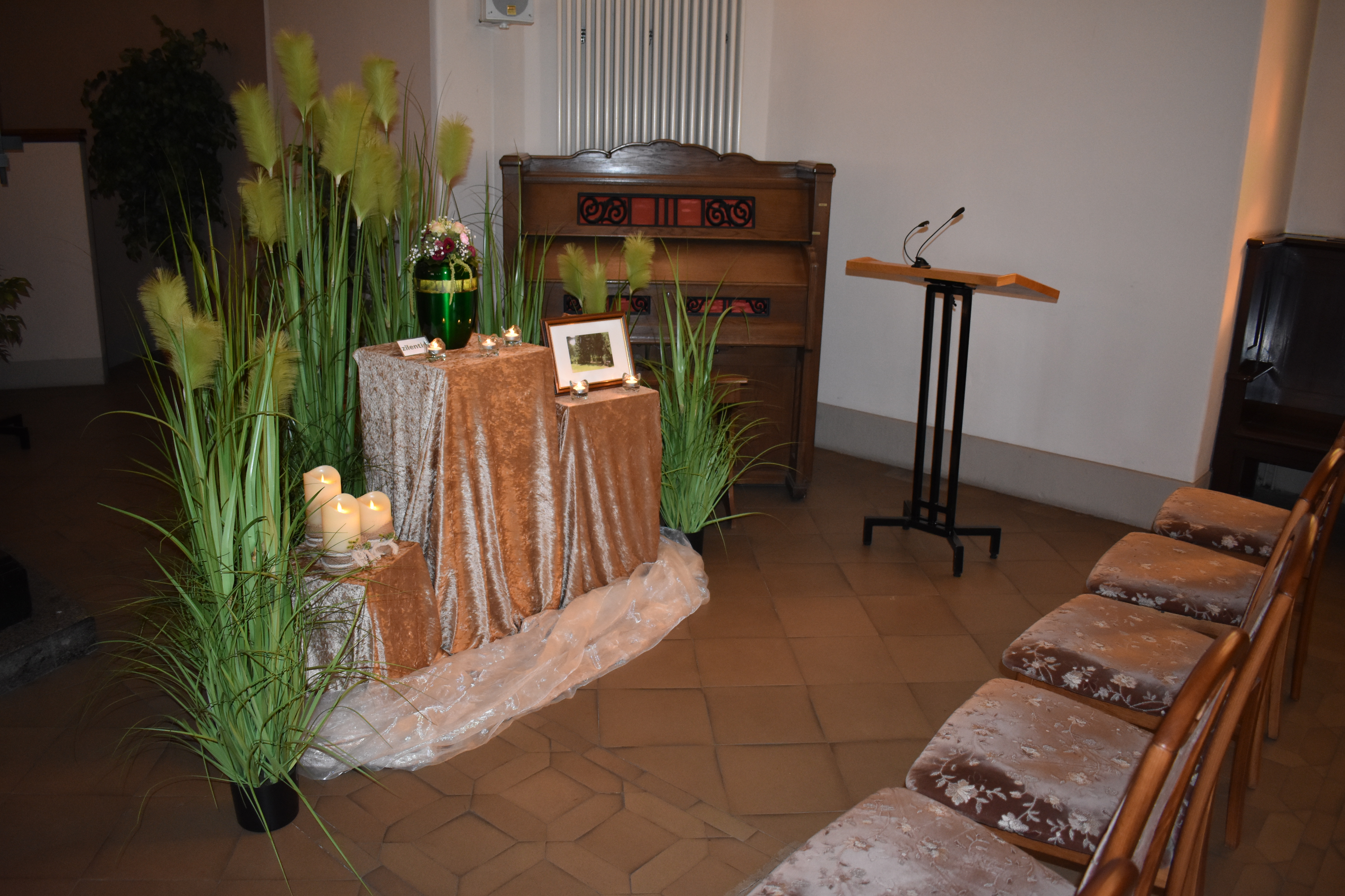 Blick in die Feierhalle Krematorium Zittau mir Urne, Blumen, Rednerpult, Harmonium und Bestuhlung